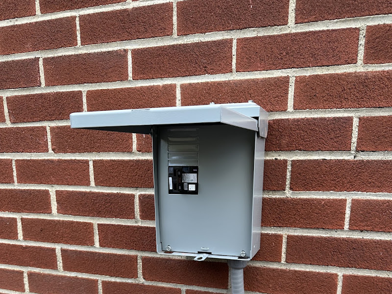 Generator transfer switch box mounted on a brick wall, a real Electrical Innovations install